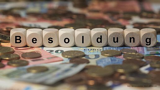 Holzwürfel mit Buchstaben im Hintergrund mit Geld, Geldscheine