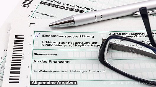 Formular Einkommensteuererklärung mit Kugelschreiber und Brille