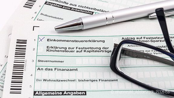 Formular Einkommensteuererklärung mit Kugelschreiber und Brille